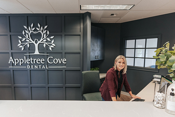 Friendly front desk staff helps a patient check in at Appletree Cove Dental